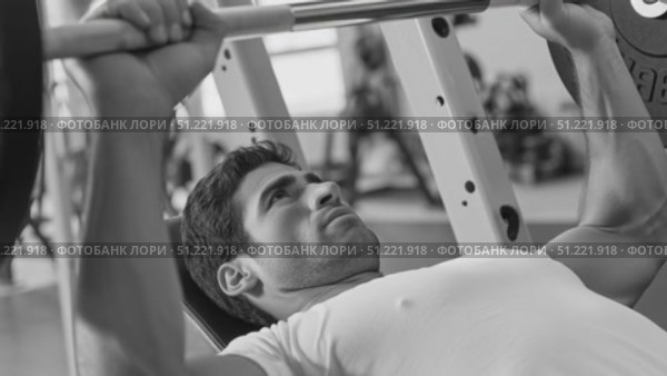 Muscular athlete bench pressing heavy weights, showcasing powerful physique and intense training commitment in monochrome gym setting. Стоковое AI-видео, аниматор Юрий Поздников / Фотобанк Лори