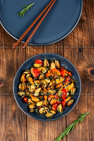 Mussels in cream sauce with tomatoes and garlic on rustic wooden table.. Plate of mussels on a table. Стоковое фото, агентство Ingram Publishing / Фотобанк Лори