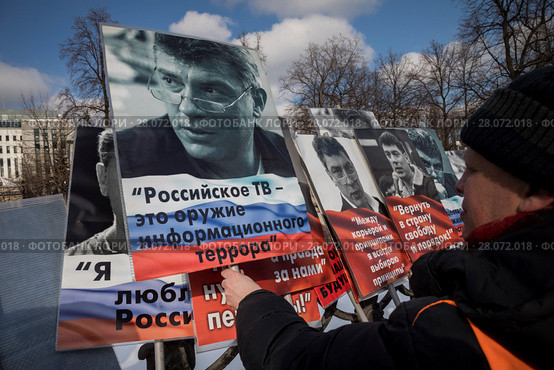 Мужчина берет плакат с портретом Бориса Немцова во время марша по бульварам города Москвы в третью годовщину с момента убийства политика Бориса Немцова, Россия, 25 февраль 2018. Редакционное фото, фотограф Николай Винокуров / Фотобанк Лори