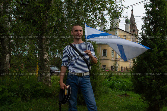 Мужчина, бывший моряк, с флагом в день ВМФ на улице Тутаева. Редакционное фото, фотограф Дмитрий Киселёв / Фотобанк Лори