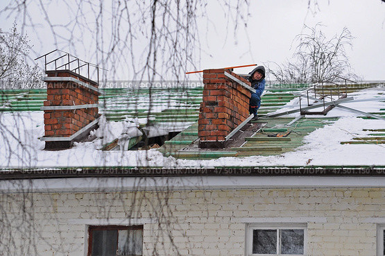 Мужчина осматривает трубу дымохода на крыше жилого дома. Редакционное фото, фотограф Лариса Вишневская / Фотобанк Лори