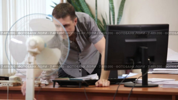 Мужчина работник офиса на работе, включает напольный вентилятор. Стоковое видео, видеограф Кекяляйнен Андрей / Фотобанк Лори