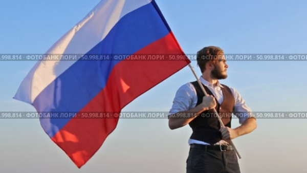 Мужчина с флагом России на фоне неба. Стоковое видео, видеограф 1Andrey Милкин / Фотобанк Лори