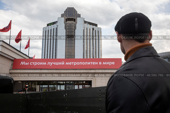 Мужчина смотрит на наземноый вестибюль станции метро "Сокольники" с надписью "Мы строим лучший метрополитен в мире" в центре города Москвы, Россия. Редакционное фото, фотограф Николай Винокуров / Фотобанк Лори