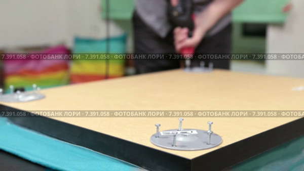 Мужчина собирает стол с помощью электрической дрели. Стоковое видео, видеограф Кекяляйнен Андрей / Фотобанк Лори