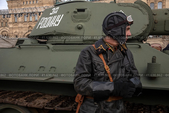 Мужчина в форме танкиста Красной армии времен 1940-х годов стоит у танка на Красной площади в городе Москве, Россия (2023 год). Редакционное фото, фотограф Николай Винокуров / Фотобанк Лори