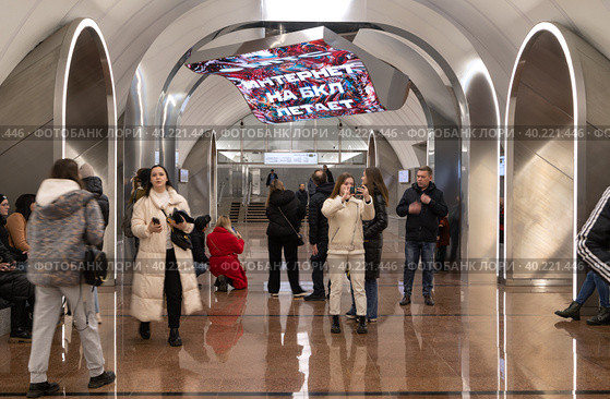 На платформе станции "Рижская" Большой кольцевой линии Московского метрополитена люди рассматривают и фотографируют световую инсталляцию «Ковёр-самолет» с надписью "Интернет на БКЛ летает" (2023 год). Редакционное фото, фотограф Наталья Николаева / Фотобанк Лори