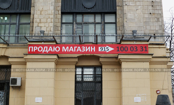 Надпись "Продаю магазин" на вывеске, висящей на стене здания (2015 год). Редакционное фото, фотограф Александр Замараев / Фотобанк Лори