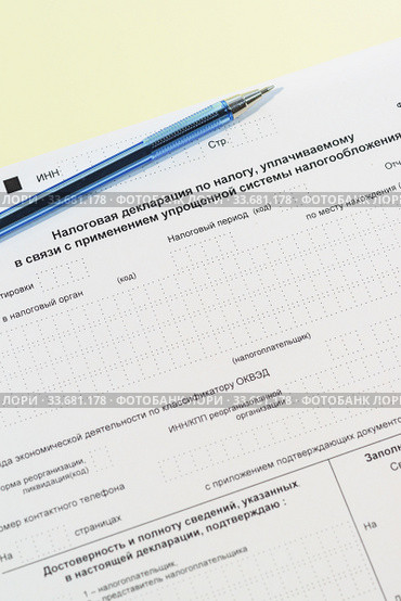 Налоговая декларация по налогу, уплачиваемому в связи с применением упрощенной системы налогообложения (КНД 1152017) и ручка на столе. Стоковое фото, фотограф Наталья Гармашева / Фотобанк Лори
