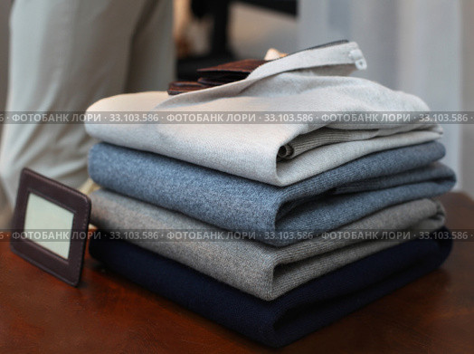 Neatly folded men sweaters on wooden shelf. Стоковое фото, фотограф Tatjana Urosevic / Smarterpix / Фотобанк Лори