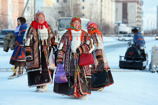 Ненецкие женщины в красивых национальных меховых одеждах идут по городу. Надым, Ямало-Ненецкий автономный округ (2018 год). Редакционное фото, фотограф Григорий Писоцкий / Фотобанк Лори