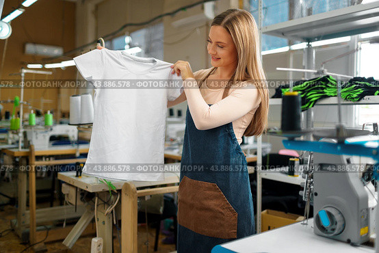 Nice woman tailor holding just sewn t-shirt. Стоковое фото, фотограф Сергей Толмачёв / Фотобанк Лори