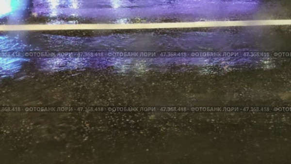 Night city street. It's raining late in the evening, puddles have formed on the road. The black asphalt is wet from the rain. Cars drive through the puddles, splashing muddy water. Стоковое видео, видеограф Andrew_Swarga / Фотобанк Лори