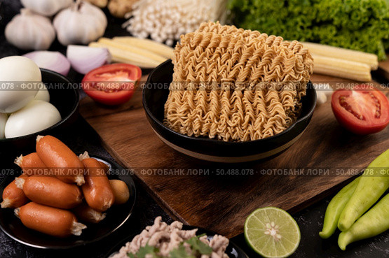 Noodles on a wooden cutting board with tomato, lime, spring onion, chili and baby corn. Стоковое фото, агентство Ingram Publishing / Фотобанк Лори