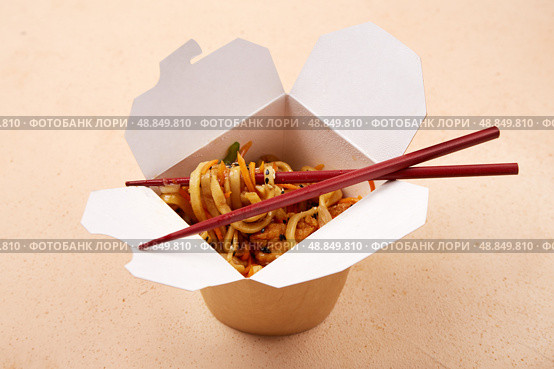 Noodles served in takeout box with chopsticks on a simple background. Стоковое фото, фотограф Виктория Тельминова / Фотобанк Лори