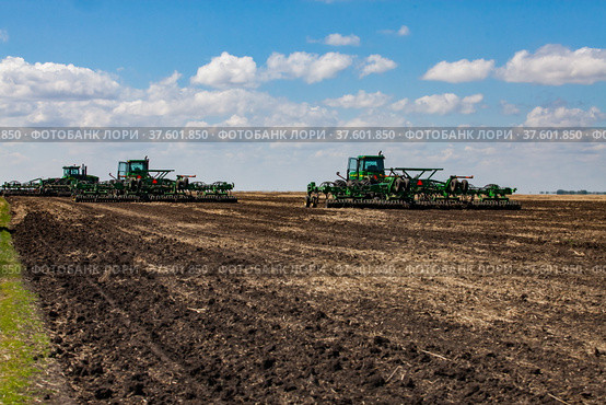 North Kazakhstan Province, Kazakhstan - May 12, 2012: Spring sowing campaign. John Deere tractors cultivating soil with harrow. Blue sky, clouds. Стоковое фото, фотограф Alexey Rezvykh / Фотобанк Лори