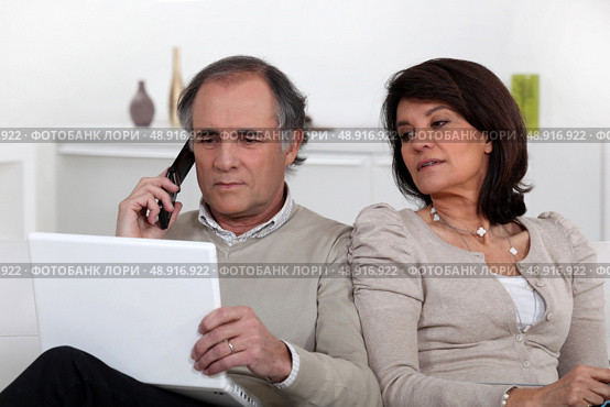 Nosy wife looking at her husband’s laptop screen. Стоковое фото, агентство Ingram Publishing / Фотобанк Лори
