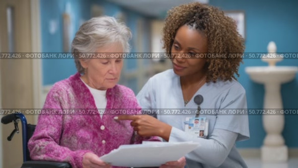 Nurse explaining medical chart to senior patient in wheelchair. Стоковое AI-видео, аниматор Юрий Поздников / Фотобанк Лори