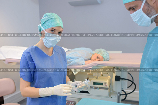 Nurse holding syringe, patient face down on bed. Стоковое фото, агентство Ingram Publishing / Фотобанк Лори