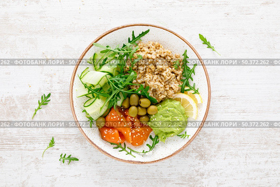 Oatmeal with salted salmon, avocado guacamole and fresh vegetable salad of arugula, cucumbers and olives. Breakfast. Top view. Стоковое фото, агентство Ingram Publishing / Фотобанк Лори