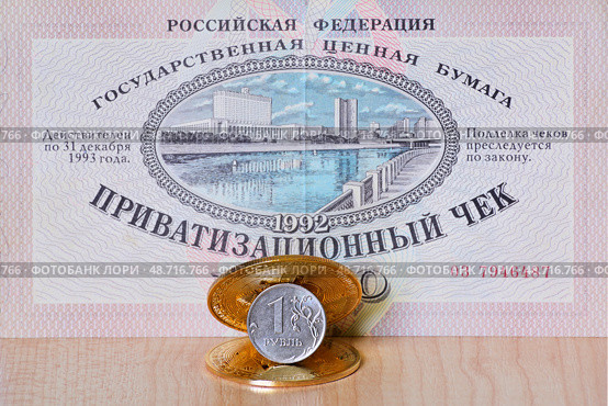 Один рубль между биткоином и эфириумом на фоне приватизационного чека (ваучера) 1992 года. Российские деньги, ценные бумаги и сувенирные монеты криптовалют. Фокус на рубле. Редакционное фото, фотограф Владимир Литвинов / Фотобанк Лори
