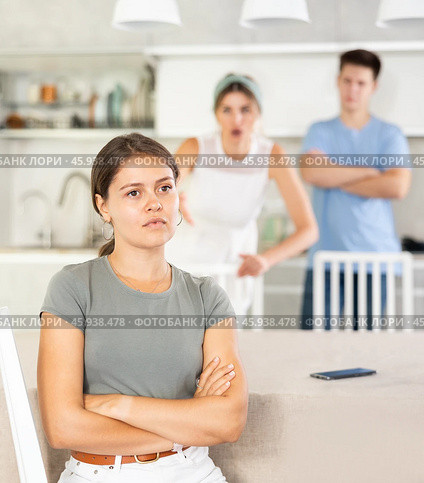 Offended young woman sitting at kitchen during argument with husband and mother-in-law. Стоковое фото, фотограф Яков Филимонов / Фотобанк Лори