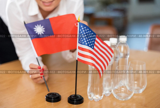 Office coordinator setting flags of Taiwan and United States on table. Стоковое фото, фотограф Яков Филимонов / Фотобанк Лори