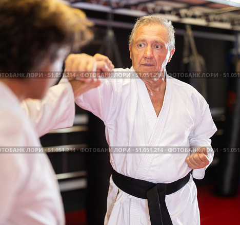Older karate fighter practicing paired kumite in dojo. Стоковое фото, фотограф Яков Филимонов / Фотобанк Лори