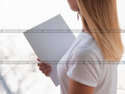 OLYMPUS DIGITAL CAMERA. high view woman holding mock up magazine. Стоковое фото, агентство Ingram Publishing / Фотобанк Лори