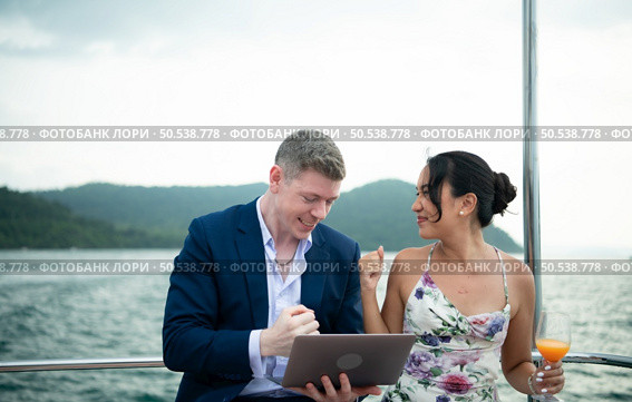 On a yacht, a businessman begins his family’s vacation. a huge project agreement was successfully closed, which was wonderful news. Стоковое фото, агентство Ingram Publishing / Фотобанк Лори