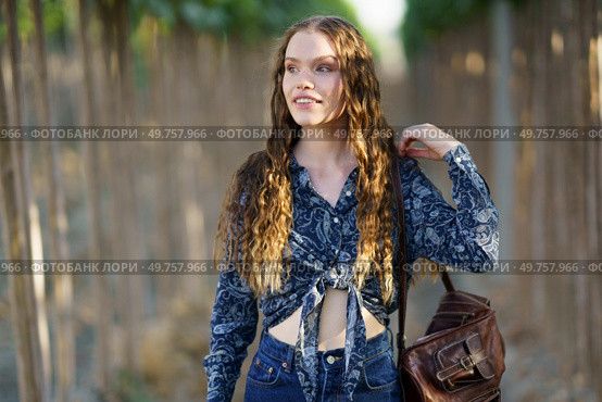 On this sunny day, a young woman with long hair enjoys a serene setting, dressed in a stylish outfit that reflects her cheerful demeanor and passion for beauty, making the moment delightful. A Joyful Young Woman with a Bright Smile Enjoying Nature in Her Casual Outfit with Long Hair. Стоковое фото, агентство Ingram Publishing / Фотобанк Лори