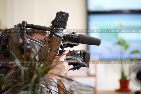 Operator with black camera is recording video in office, shallow dof. Стоковое фото, фотограф Losevsky Pavel / Фотобанк Лори