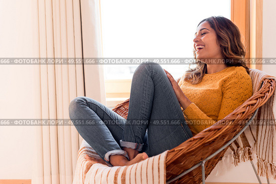 Optimistic woman sitting in a confortable rattan chair at home. Стоковое фото, агентство Ingram Publishing / Фотобанк Лори