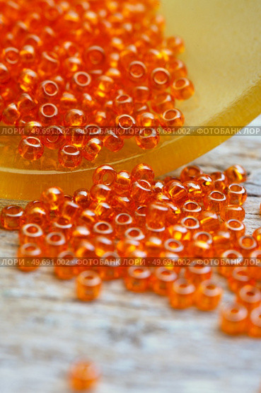 orange  small beads around old style wooden background. macro shot. hobby and hand made concept. Стоковое фото, агентство Ingram Publishing / Фотобанк Лори