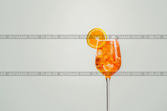 Оранжевый коктейль апероль шприц (aperol spritz) с кусочками льда и долькой апельсина в бокале на светлом фоне. Стоковое AI-изображение, AI-художник Кирилл Сиротюк / Фотобанк Лори