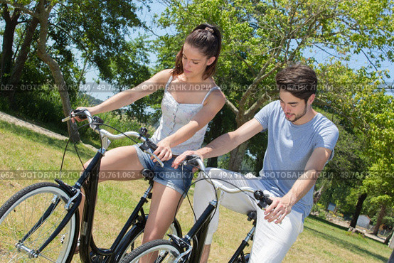 outdoor portrait of teenage couple riding bicycles in nature. Стоковое фото, агентство Ingram Publishing / Фотобанк Лори