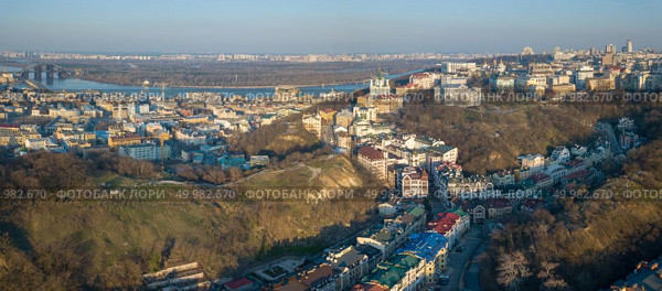 Panoramic aerial view from the drone, bird’s eye view to the Vozdvizhenka, Podolsky bridge, St. Andrew’s Church, National Museum of Ukrainian History, Andreevsky descent, Truhanov Island.. A bird’s eye view, aerial panoramic view from drone to the Podol district, oldest historical center of Kiev, the Dnieper River and the left bank of Dnieper in the city of Kiev, Ukraine. Стоковое фото, агентство Ingram Publishing / Фотобанк Лори