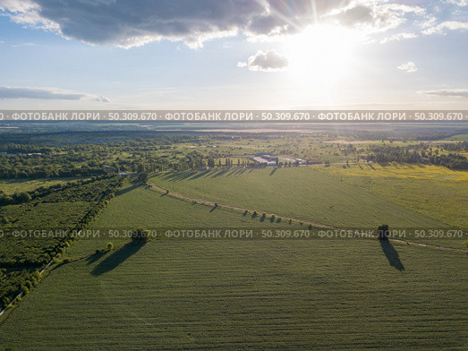 Panoramic bird’s eye view from drone of outdoors landscape above farmlands, agricultural fields, and forests on bright sky background on a summer sunny day. Ukraine, Uman city.. Aerial panoramic drone view of the countryside area on a sunny day. Стоковое фото, агентство Ingram Publishing / Фотобанк Лори