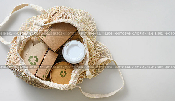 Paper food packaging with recycling signs in a textile shopping bag. Nature protection and zero waste concept. Free space. Стоковое фото, фотограф Никита Бурденков / Фотобанк Лори