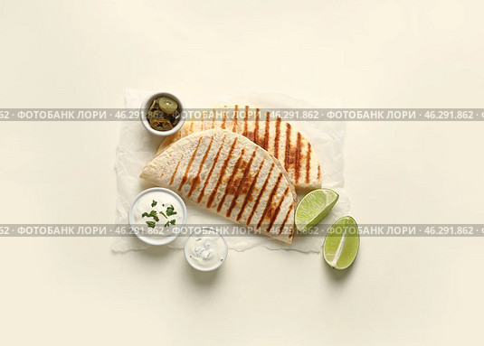 Parchment with tasty quesadillas, lime, sauces and pickled jalapenos on white background. Стоковое фото, фотограф Pixel_shot / Фотобанк Лори