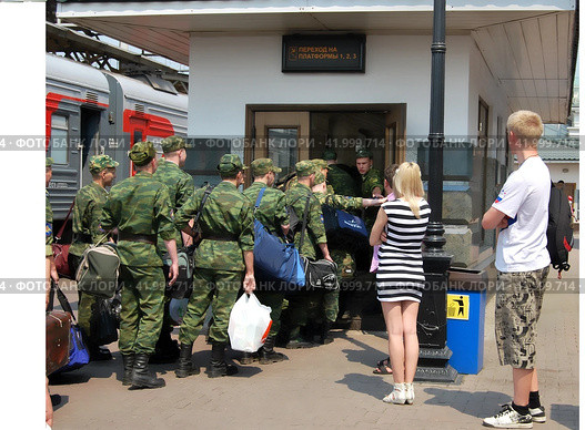 Парень и девушка смотрят как новобранцы в военной форме следуют к переходу на ЖД платформу к поезду (2012 год). Редакционное фото, фотограф Ольга Зражевская / Фотобанк Лори