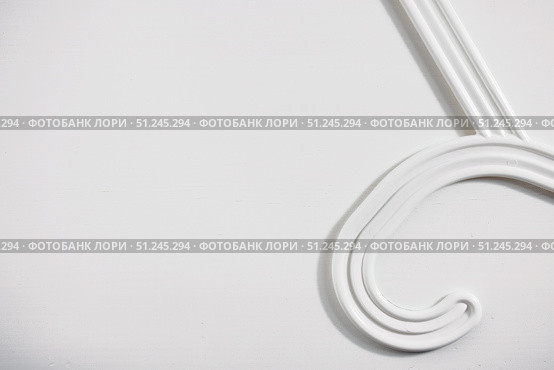 Part of a white clothes hanger on a white wooden background. Top view, copy space for text. Стоковое фото, фотограф Зарифа Арсланова / Фотобанк Лори