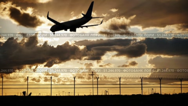 Passenger airplane landing at sunset over airport fence. Стоковое видео, видеограф Mikhail Davidovich / Фотобанк Лори