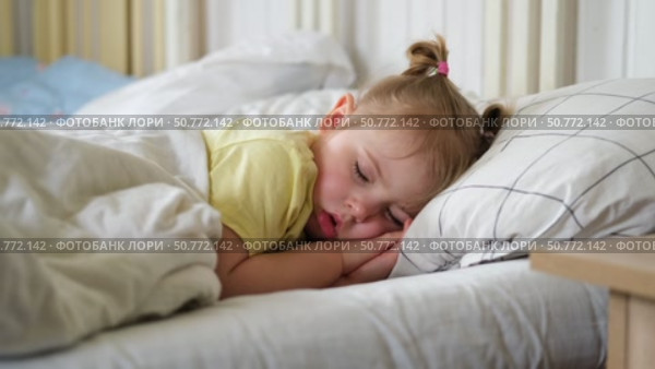 Peaceful adorable baby sleeping on a bed at home. Slumbering little child. Two years old girl sleeps peaceful at domestic room interior background. Serene dream. Cute face close up. Deep kid slumber. Стоковое видео, видеограф Марина Демидюк / Фотобанк Лори
