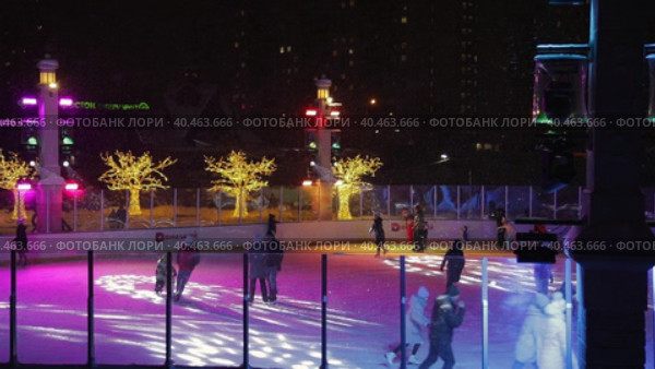 People skate in the evening on a lighted ice rink. A blizzard is raging and snow is falling. Zelenograd, Russia 28.01.2022. Редакционное видео, видеограф Юрий Поздников / Фотобанк Лори
