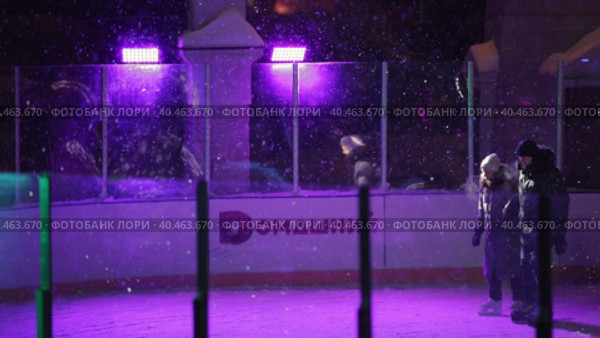 People skate in the evening on a lighted ice rink. A blizzard is raging and snow is falling. Zelenograd, Russia 28.01.2022. Редакционное видео, видеограф Юрий Поздников / Фотобанк Лори