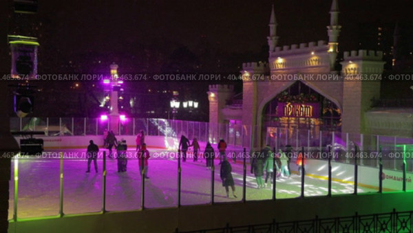 People skate in the evening on a lighted ice rink. A blizzard is raging and snow is falling. Zelenograd, Russia 28.01.2022. Редакционное видео, видеограф Юрий Поздников / Фотобанк Лори