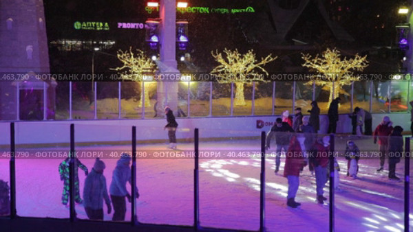 People skate in the evening on a lighted ice rink. A blizzard is raging and snow is falling. Zelenograd, Russia 28.01.2022. Редакционное видео, видеограф Юрий Поздников / Фотобанк Лори