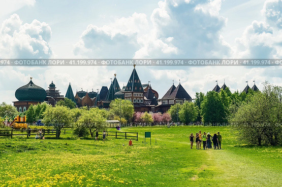 People walking on grass field in park in sunny spring day. On the background is wooden palace or castle of Tsar Aleksey Mikhailovich in Kolomenskoye. Редакционное фото, фотограф Константин Григорьев / Фотобанк Лори