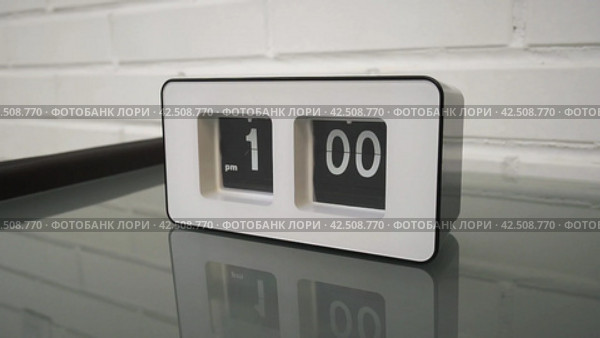 Перекидной циферблат часов будильника. Flip clock mechanism. 1:00 PM. Flip clock watch face. White brick wall in the background. Slow motion 240 fps. Стоковое видео, видеограф EStarodubov / Фотобанк Лори